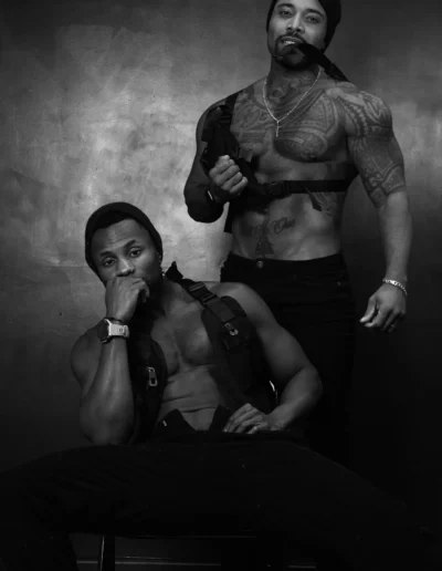 Deux gogo danseurs en studio, photographie en noir et blanc, l'un assis l'autre debout
