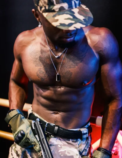 Gogo danseur en tenue militaire et casquette camouflage sur scène, éclairage rouge et bleu