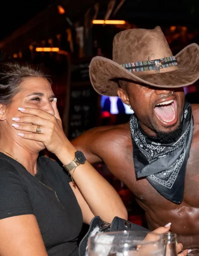 Gogo danseur en costume de cowboy faisant rire une invitée lors d'une soirée