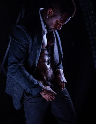 Gogo danseur en veste de costume sur torse nu, portrait en clair-obscur