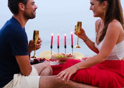 Couple trinquant au champagne lors d'un dîner romantique installé sur le sable