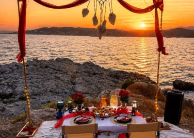 Longue table basse en palettes sur le sable, tournesols, ananas et chaises basses devant les cabanons de plage
