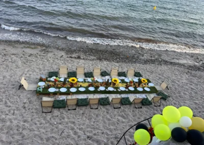 Vue aérienne d'une table d'anniversaire dressée sur le sable, lettres Happy Birthday, tournesols et ballons