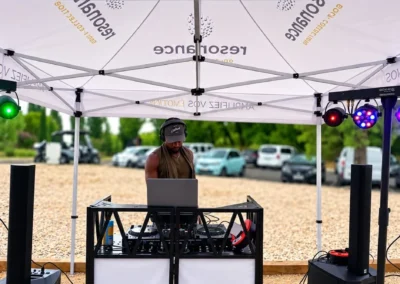 Régie DJ installée sous un barnum en extérieur, enceintes et jeux de lumière