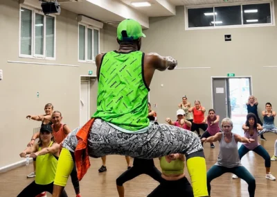 Animateur de Zumba menant un cours en salle de danse devant un groupe de participantes