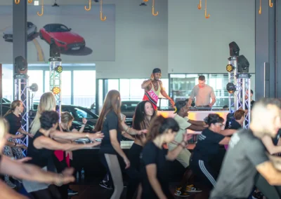 Masterclass de Zumba animée sur scène avec DJ, sous un plafond de parapluies rouges